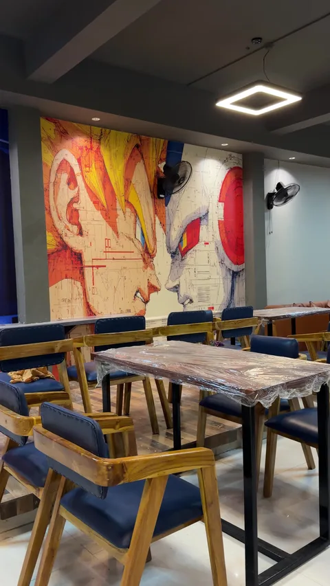 Cafe tables and blue chairs beside the illustrated walls